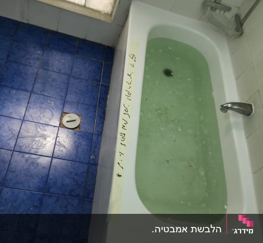 אמבטיה עם מים ירקרקים ורצפת אריחים כחולה